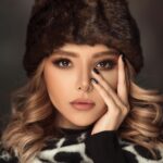 Close-up portrait of a woman in winter fashion with elegant makeup and fur hat.