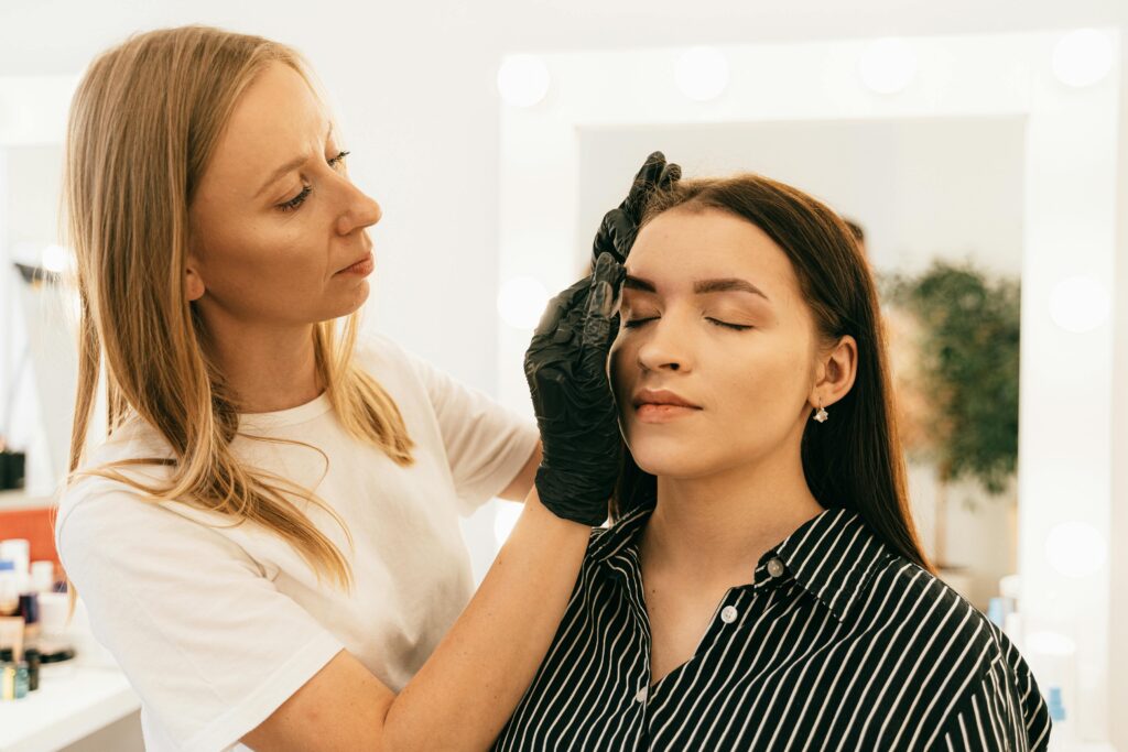 Makeup artist applying foundation in a well-lit studio setting, focusing on beauty and preparation.