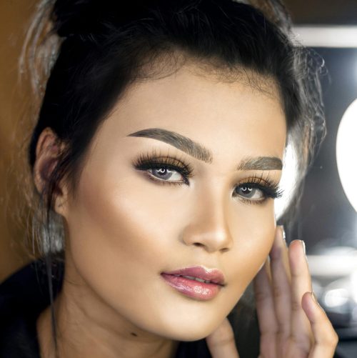 Close-up portrait of a woman with professional makeup and styled hair, exuding confidence and elegance.